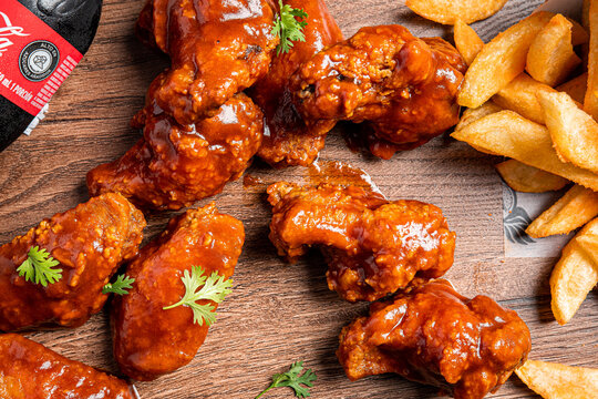 alitas bbq en una mesa de madera y papas regadas