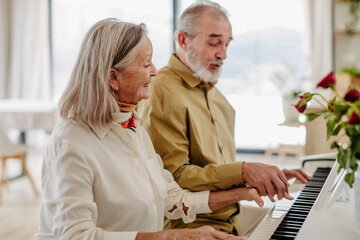 Senior couple playing on piano together at home. - Powered by Adobe
