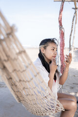 Hispanic woman doing makeup on a hammock at the beach