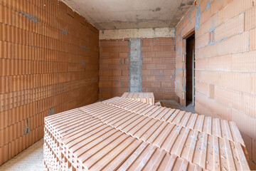 Unfinished room interior of building under construction. Brick red walls. New home.