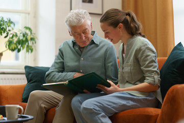 Senior man with his grandaughter looking family photo album.