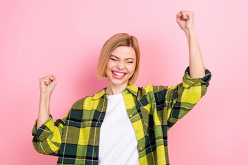 Photo portrait of attractive young woman raise fists excited winner dressed stylish checkered yellow look isolated on pink color background