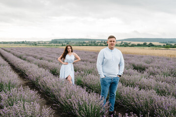 Couple in violet lavender field of flowers. Man and woman standing and enjoys floral glade, summer nature. Loving family walking at sunset. France, Provence. Honeymoon trip, traveling. Closeup