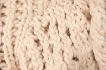 A fragment of beige knitted fabric, knitted from white sheep wool.