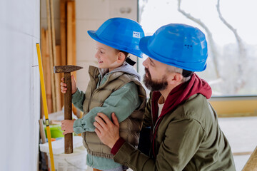 Father and his little son working on their unfinished house.