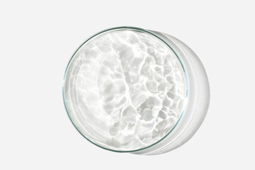 Petri dish on a light background with liquid, water. Splashes of water. The waves in the Petri...