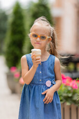 a little happy girl with down syndrome eats ice cream in the summer on a walk
