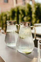 Modern Glass Pitcher of Ice Water infused with Lime Slices on a Grey Outdoor Patio Bar