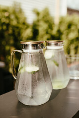 Modern Glass Pitcher of Ice Water infused with Lime Slices on an Outdoor Patio Bar