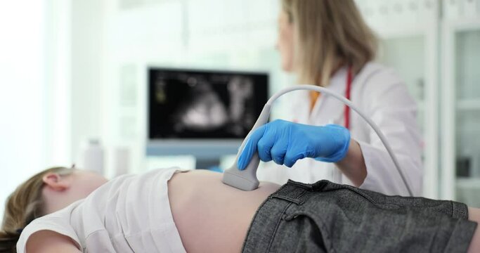 Attentive doctor checks stomach of little girl with modern ultrasound equipment. Woman uses medical equipment looking at screen with image slow motion