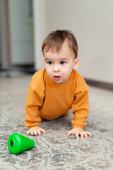 Little boy playing on the floor in home. Small child with colourful toy.