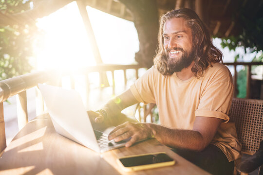 Happy Caucasian man enjoying online networking in social media during distance job on modern laptop, cheerful skilled copywriter creating funny content text via application on digital netbook