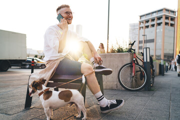 Male with dog having fun during phone call outdoors