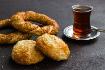 Traditional Turkish crispy,sesame bagels and a glass of tea on the black surface with sesame seeds