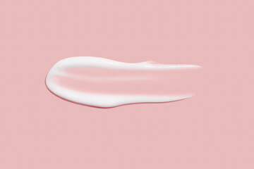 A dab of cosmetic cream. Light, smooth surface. Texture of spreadable cream. Liquid cream smear. On a pink background.