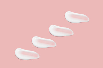 Lots of smears of cosmetic cream. Light, smooth surface. Texture of spreadable cream. Liquid creamy strokes. On a pink background. Cosmetic background, banner.