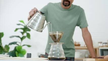 Asian man on weekend breaks from work, Wake up in morning wanting live chill life, wear comfortable pajamas standing drip coffee in kitchen, lowering head, inhaling coffee after coffee drip.