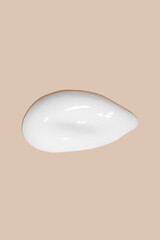 The flowing cream on a beige background. Smudged flowing smear of cosmetic cream.