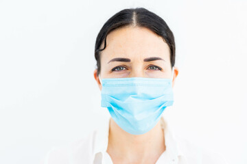 a blue masked brunette doctor or nurse in a hospital working in a clean and sterile asepctic environment in a laboratory