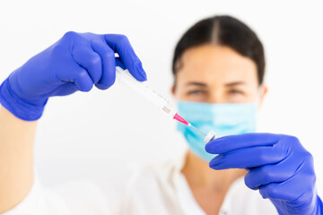 A doctor preparing a vaccine syringe in blue gloves and a mask for a covid 19 vaccination