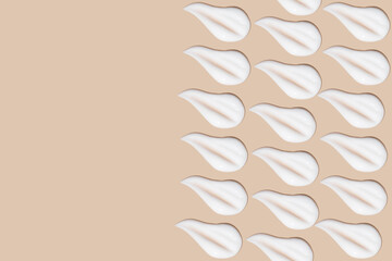 a set of strokes of white cream on a beige background.