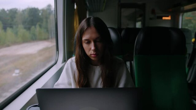 Handheld camera. A woman works in a modern train carriage. A freelancer is sitting in front of a laptop