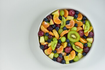 Healthy fresh fruit salad bowl on white background. Top view. Healthy food concept, healthy high vitamin fruit, mixed fruit background.