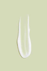The flowing cream on a green background. Smudged flowing smear of cosmetic cream.