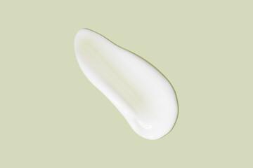 The flowing cream on a green background. Smudged flowing smear of cosmetic cream.