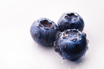 Three blueberries with drops, on a white background. Advertising banner, fresh wet blueberries
