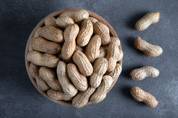 Bowl full of shelled and roasted peeled peanuts on black background,top view 