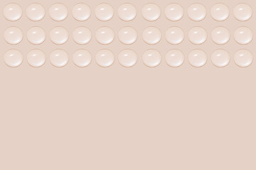 Drops of transparent gel or water in rows. On a beige background.