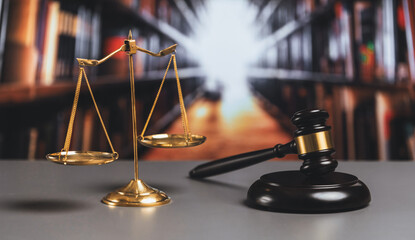 Shiny golden balanced scale and wooden gavel in court library background as symbol of justice and...