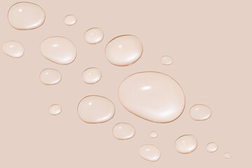 Drops of transparent gel or water in different sizes. On a beige background.