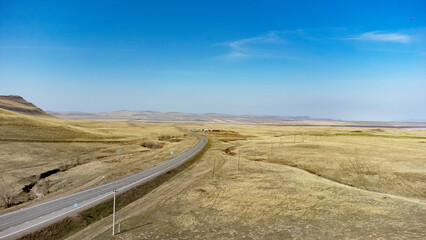 Aerial view of a road leading through desert land and hills. Yellow sand soft earth view.