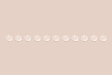 Drops of transparent gel or water in a row. On a beige background.