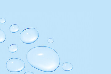 Drops of transparent gel or water in different sizes. On a blue background.