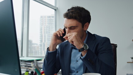 Serious manager speaking mobile phone at workplace. Worried sales man talking
