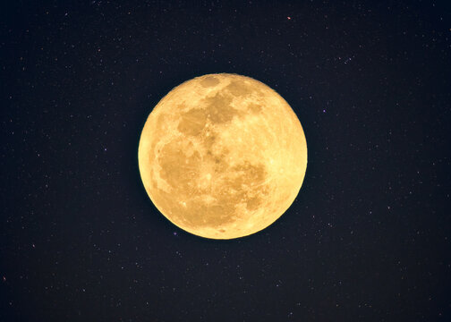 Yellow full moon with crater textured glowing with starry in night sky