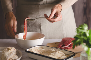 Close up of female hands cooking Argentinian milanesas in the kitchen at home.
