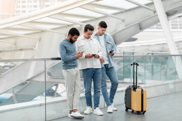 Fototapeta na wymiar Three Passengers Guys Using Social Media On Smartphones At Airport