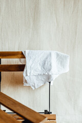 White clothing item hanging on a wooden chair. Minimalist modern interior background in scandinavian style. Minimalistic concept.