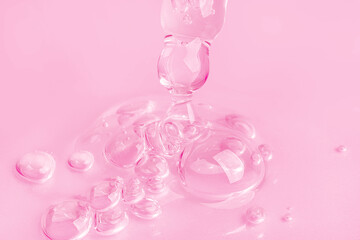 Dropping gel from an eyedropper on a pink background. Cosmetics Lab. Serum, gel, retinol, oil.