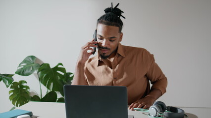 Positive freelancer talking phone in light office closeup. Man working laptop