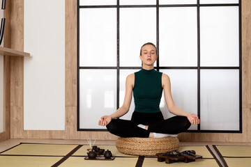 Young Slim brunette Girl practicing yoga, wearing sportswear. incense sticks and tea set lying on...