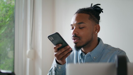 Black hair businessman talking phone speaker at home. Man picking cellphone down