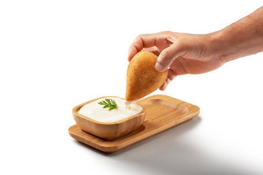 Coxinha, Traditional Brazilian Snack, Stuffed With Chicken And Fried. Hand Holding The Coxinha And Dipping It In Mayonnaise. Isolated On White Background For Creating Digital Arts. Chicken Drumstick