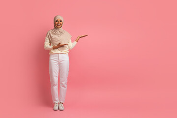 Nice Promo. Smiling Muslim Woman In Hijab Poiting Aside At Copy Space