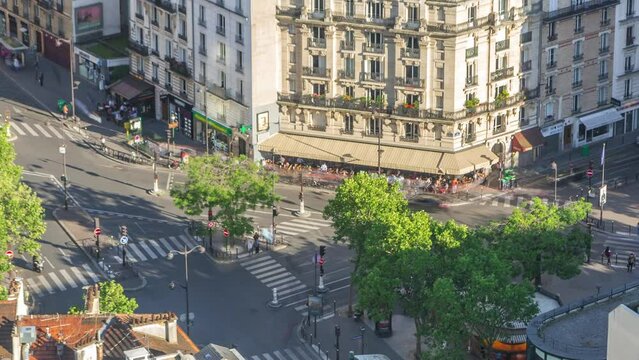Aerial overview above houses rooftops in a Paris timelapse. Evening view with traffic on intersection bebore sunset and people in caffee