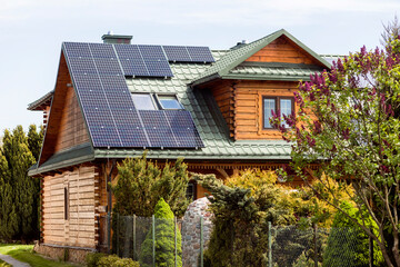 Solar panels on Roof of Old Wooden House in Countryside. Mansard Rooftop with Skylight Windows and Solar Panel System.